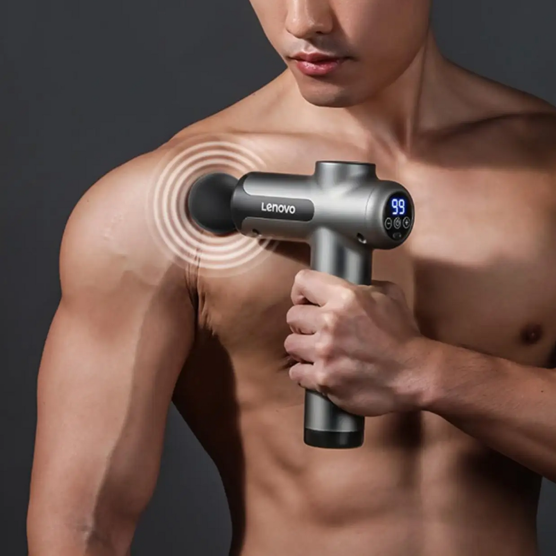 A shirtless man uses a massage device on his shoulder muscles.